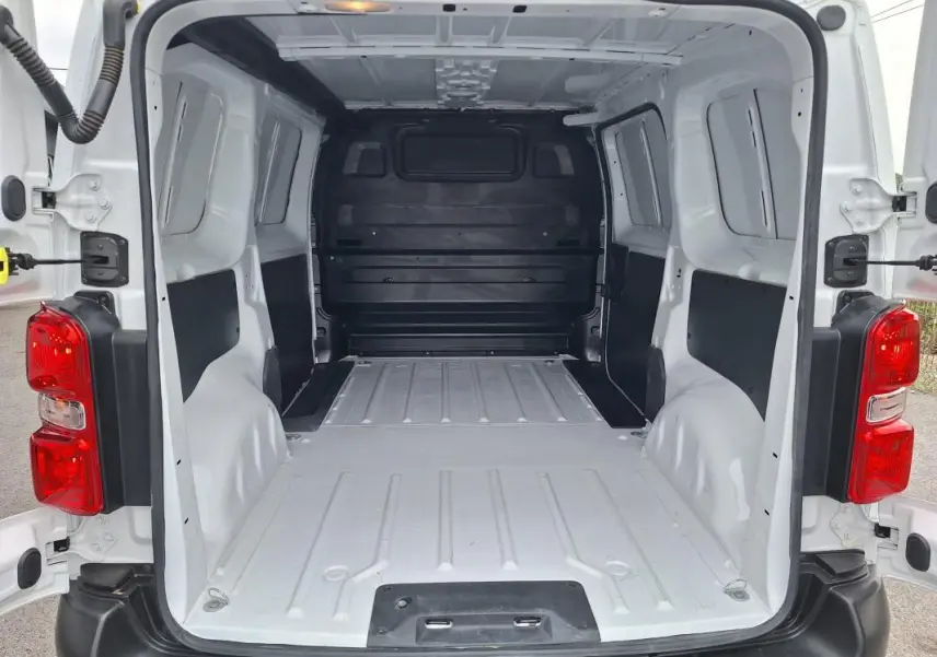 Vue arrière ouverte du fourgon blanc Opel Vivaro 2025, montrant l’espace de chargement vide et les feux arrière rouges.