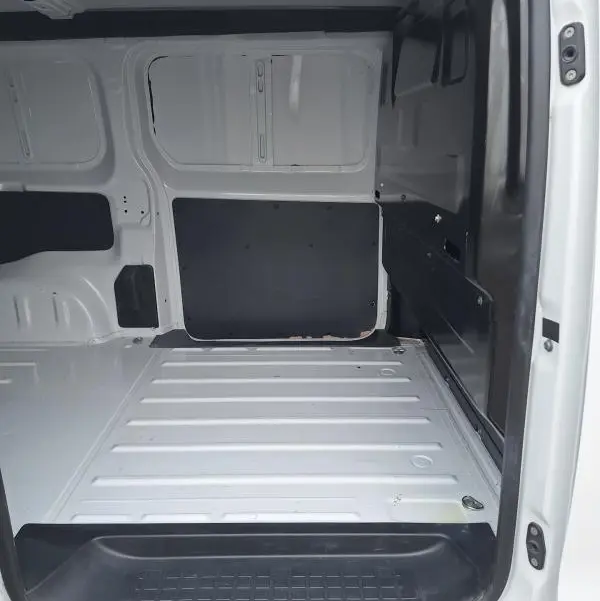 Vue intérieure de la zone de chargement du fourgon Opel Vivaro blanc, avec porte latérale ouverte et plancher métallique.