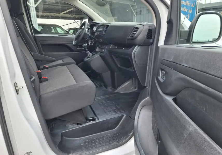 Vue intérieure côté conducteur de l’Opel Vivaro blanc 2025, montrant les sièges avant et le tableau de bord.