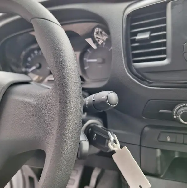 Vue rapprochée de l’intérieur noir du tableau de bord et du volant de l’Opel Vivaro blanc, avec clé insérée dans le contact.