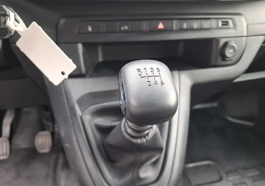 Gros plan sur le levier de vitesses manuel noir de l’Opel Vivaro 2025, intérieur gris et tableau de bord sobre.