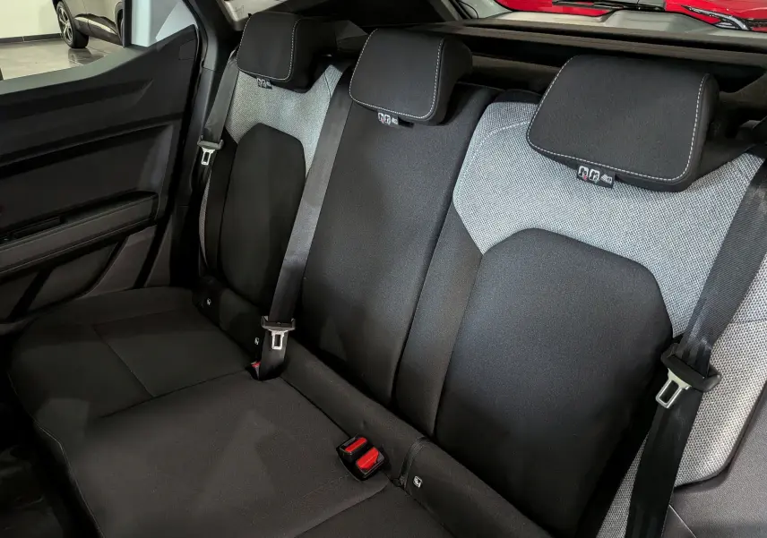 Vue intérieure du siège arrière du Dacia Duster Hybrid-G 150 CH 4x4, tissu noir et gris avec ceintures de sécurité visibles.