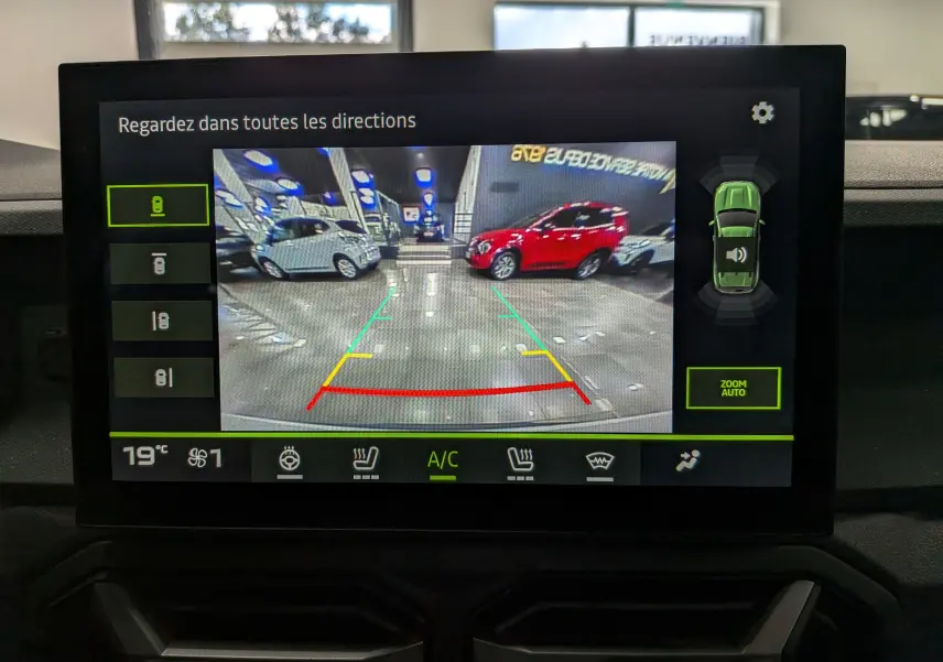 Vue caméra 360 du Dacia Duster blanc Glacier en stationnement intérieur, avec lignes d’aide au recul colorées.