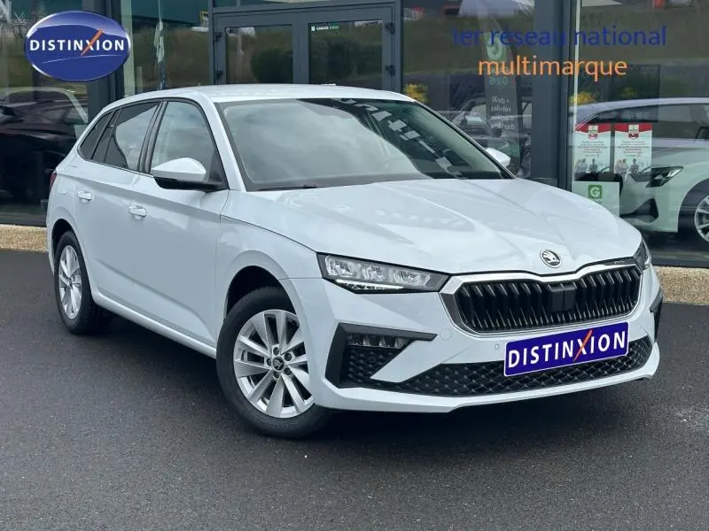 Skoda Scala blanc cristal vue 3/4 avant droit, calandre noire et jantes alu visibles sur parking.