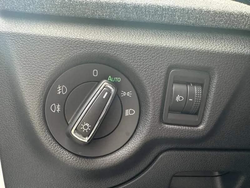 Gros plan sur la commande des phares avec sélecteur rotatif et molette de réglage d’intensité dans un Skoda Scala blanc cristal.