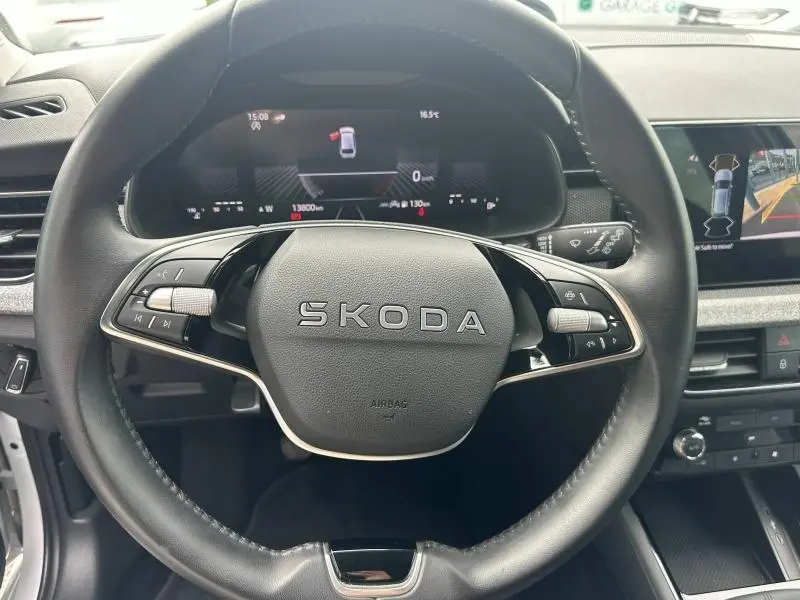 Vue centrée sur le volant cuir noir SKODA avec tableau de bord numérique et écran tactile à droite, intérieur moderne.