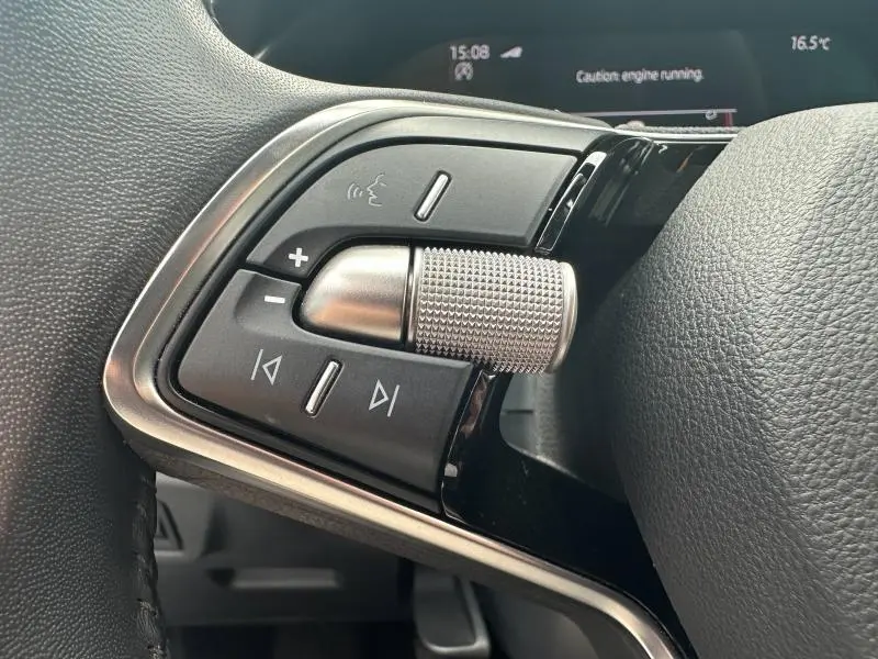 Gros plan sur les commandes multifonctions en métal et plastique noir du volant cuir d'une Skoda Scala blanc cristal.