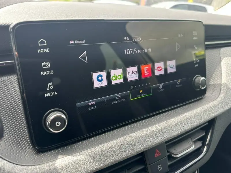 Écran tactile central du tableau de bord de la Skoda Scala blanc cristal, affichant les stations radio FM.