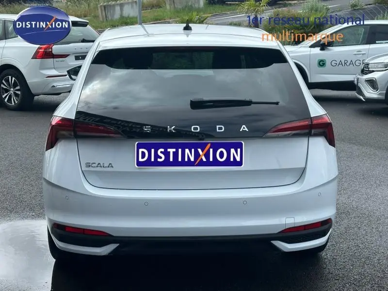 Vue arrière d'une Skoda Scala blanc cristal avec feux arrière LED et lunette arrière teintée sur parking.