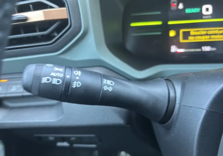 Gros plan sur la commande des feux à gauche du volant dans l'habitacle du Dacia Duster Hybrid-G 150 noir nacré 2026.