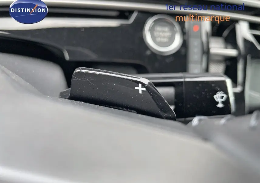 Gros plan sur la palette de changement de vitesse "+" du volant d'un Peugeot 3008 Hybrid noir métal, intérieur moderne.