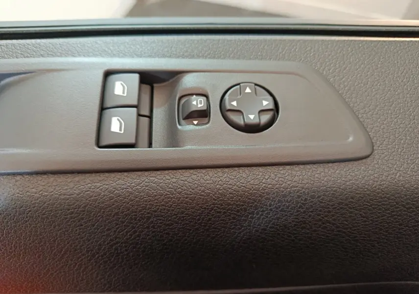 Gros plan sur les commandes de réglage des rétroviseurs et des vitres sur la porte intérieure d'un Citroën Jumpy XL noir.