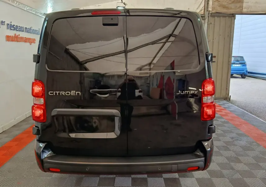 Vue arrière du Citroën Jumpy XL noir 2025, portes battantes fermées et feux arrière allumés en intérieur.