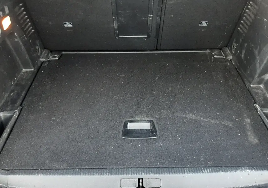 Coffre ouvert vu de face du Peugeot 3008 2023, espace de chargement noir avec tapis plat et éclairage intérieur.