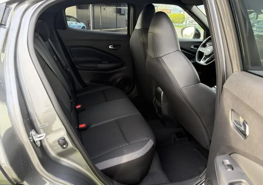 Vue intérieure côté gauche sur la banquette arrière noire et les sièges avant du Nissan Juke II 1.6 Hybrid N-Connecta.