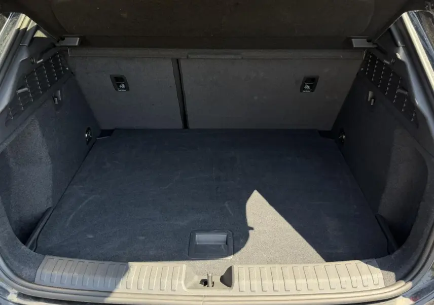 Coffre ouvert vu de l'arrière d'une Audi A3 Sportback 2025 Noir Mythe, espace de chargement vide et tapis noir.