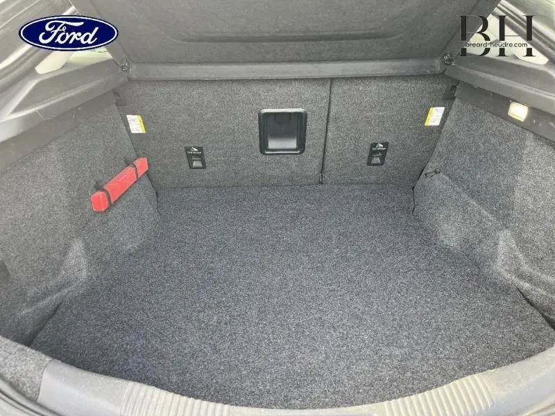 Coffre spacieux et propre de la Ford Mondeo 2.0 TDCi gris Magnetic, vu de face avec revêtement gris et éclairage intérieur.