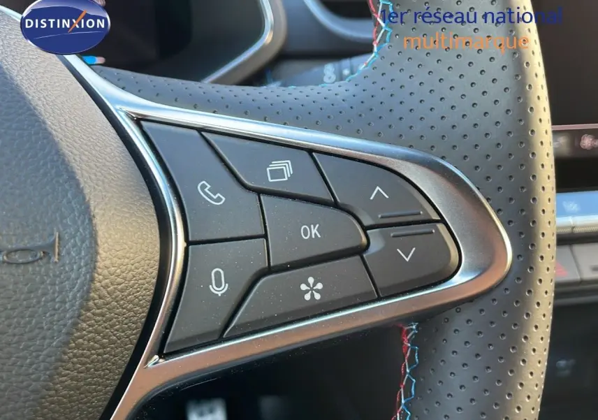 Gros plan sur les commandes au volant en cuir perforé avec surpiqûres tricolores du Renault Captur E-Tech hybride 2025.