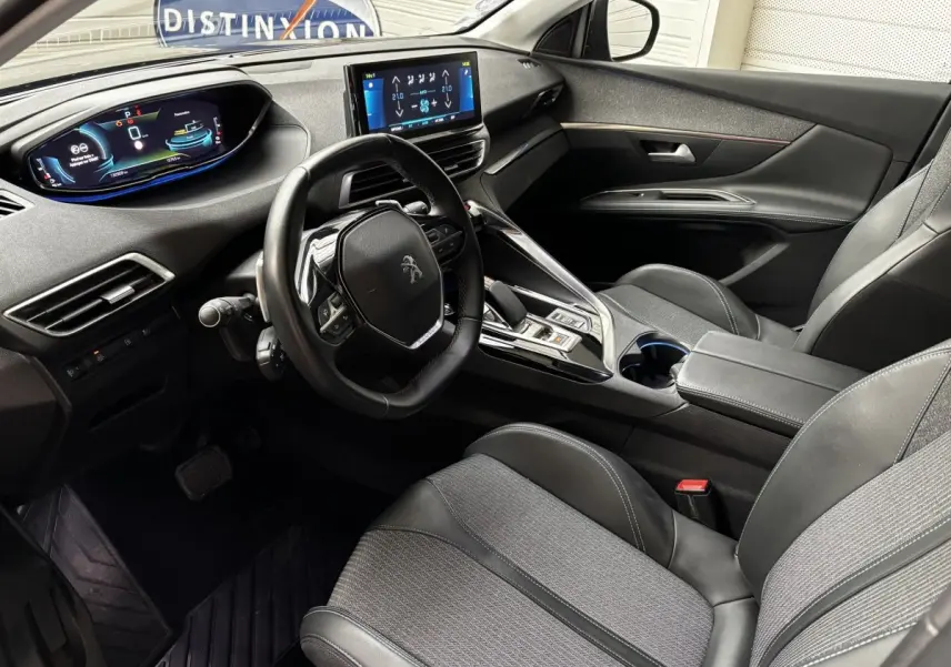 Intérieur avant droit du Peugeot 3008 hybride gris foncé, volant cuir, écran tactile et tableau de bord numérique.