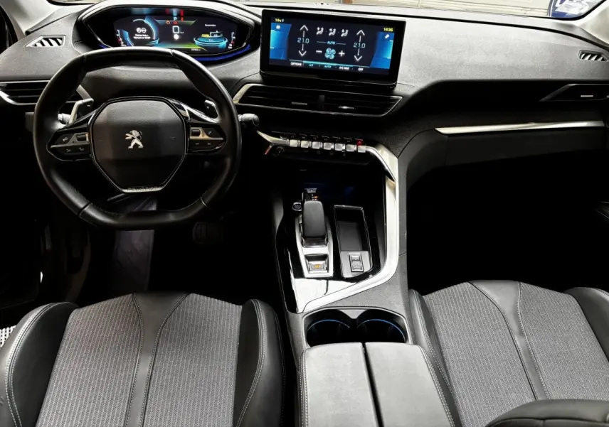 Vue intérieure avant du Peugeot 3008 gris foncé, volant cuir, écran tactile central et console moderne.