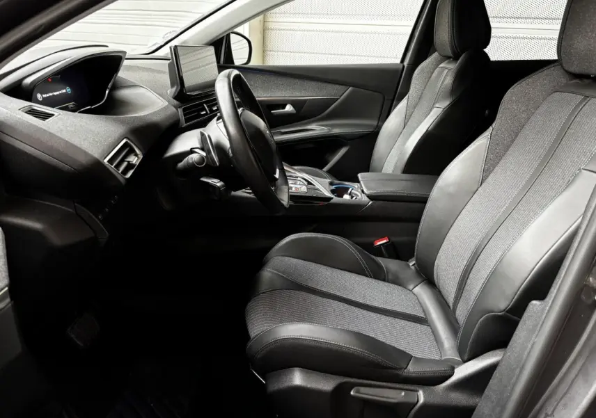 Intérieur avant droit du Peugeot 3008 hybride 2021 avec sièges cuir et tissu gris, tableau de bord numérique et écran tactile.