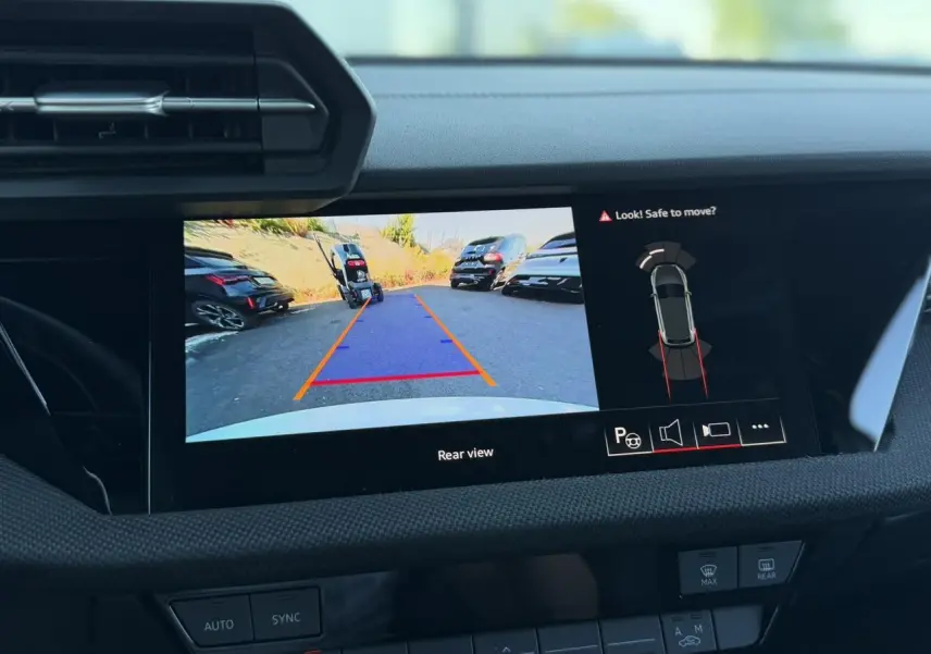 Écran intérieur affichant la caméra de recul et l'aide au stationnement d'une Audi A3 Sportback blanche Glacier.