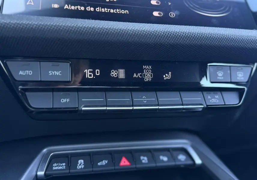 Gros plan sur la console centrale noire de l’Audi A3 Sportback blanche, affichant la climatisation digitale et les commandes.