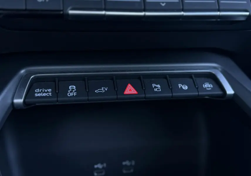 Gros plan sur la rangée de boutons de commande noire dans l'habitacle de l'Audi A3 Sportback blanc Glacier.
