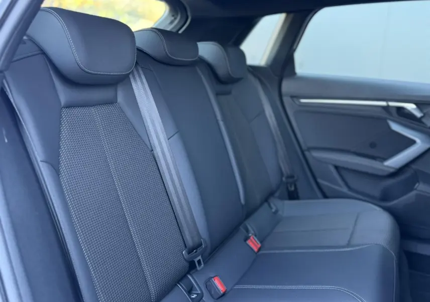 Vue intérieure des sièges arrière en tissu noir de l'Audi A3 Sportback 2025, avec ceintures de sécurité visibles.
