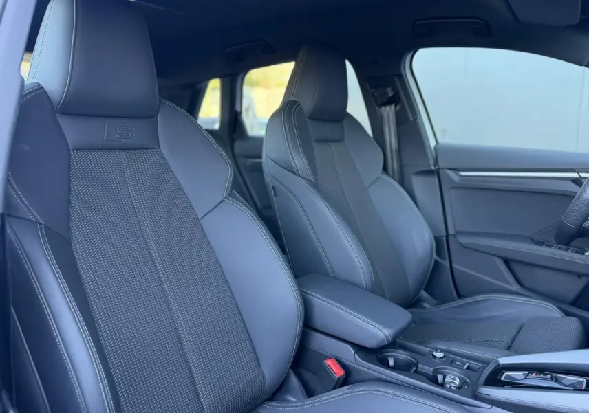 Vue intérieure côté droit des sièges sport noirs avec logo S embossé et accoudoir central coulissant de l'Audi A3 Sportback 2025.