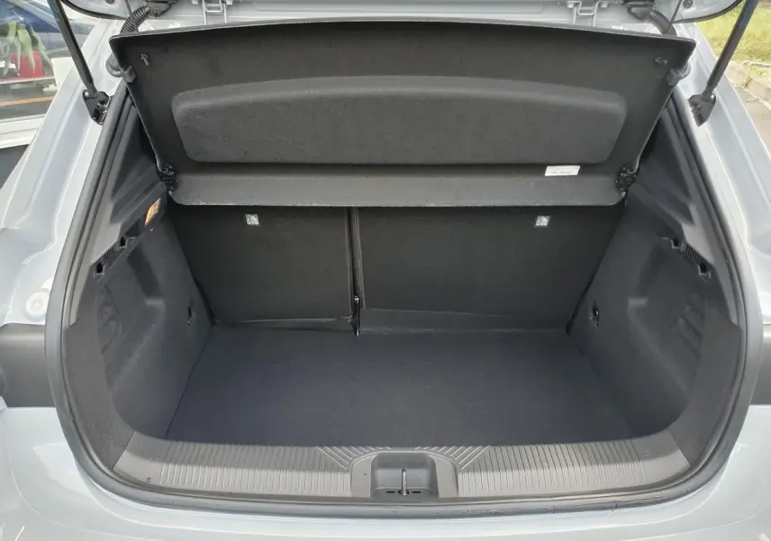Coffre ouvert vu de l'arrière d'une Renault Clio VI gris Rafale, montrant l'espace de chargement vide et la tablette arrière relevée.