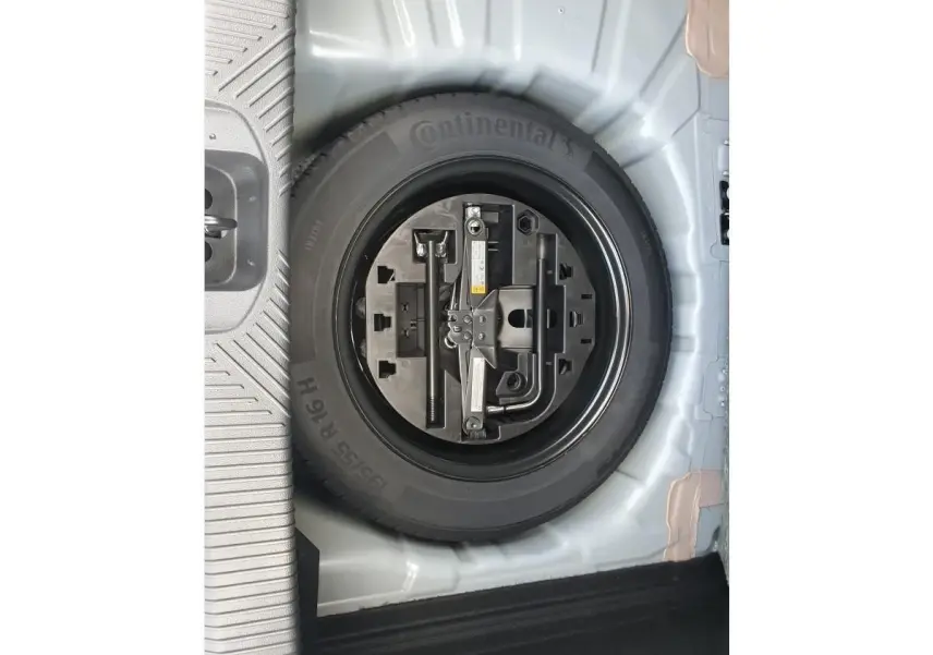 Gros plan sur la roue de secours noire avec outils intégrés dans le coffre d’une Renault Clio VI gris Rafale.