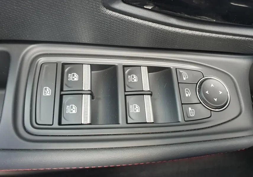 Gros plan sur les commandes de lève-vitres et rétroviseurs côté conducteur de la Renault Clio VI gris Rafale.