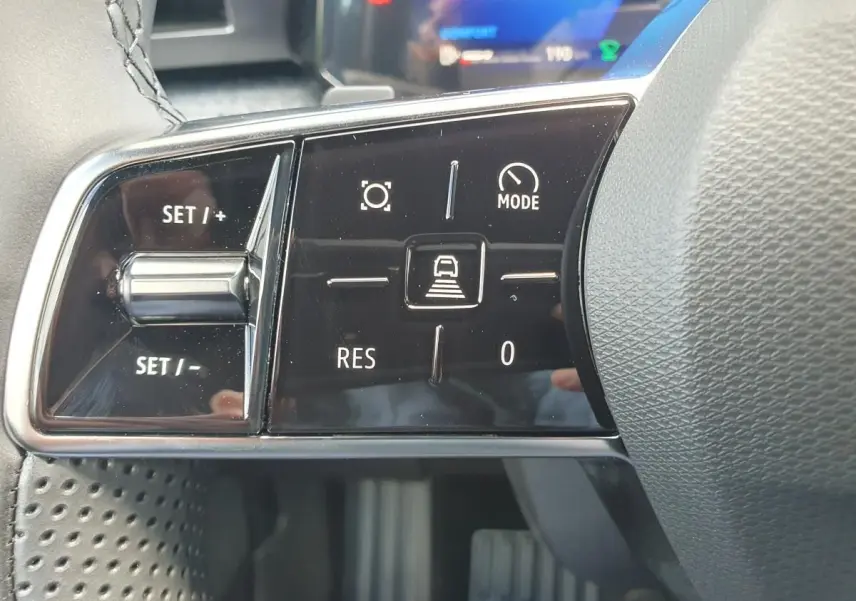 Gros plan sur les commandes au volant noir de la Renault Clio VI, avec boutons de régulateur de vitesse et mode conduite.