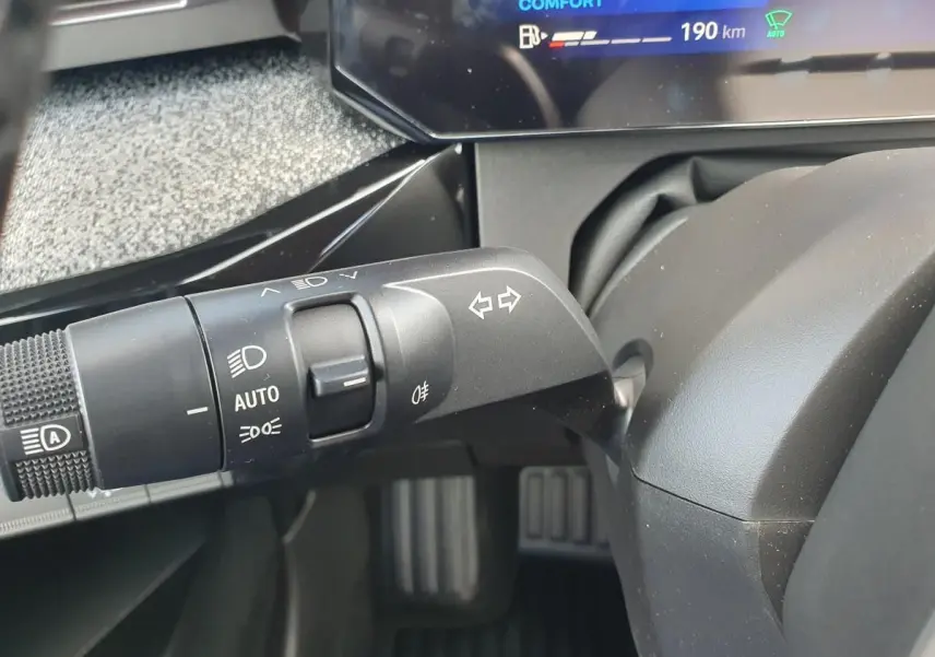 Gros plan sur la commande des feux et clignotants à gauche du volant dans l’habitacle de la Renault Clio VI gris Rafale.