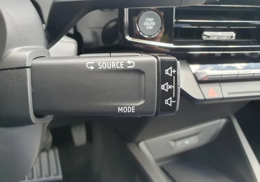 Gros plan sur la commande multimédia au volant de la Renault Clio VI, avec bouton start engine stop en arrière-plan.