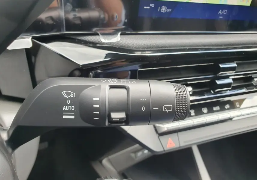 Gros plan sur la commande d’essuie-glace noire à gauche du volant dans l’habitacle gris et noir de la Renault Clio VI.
