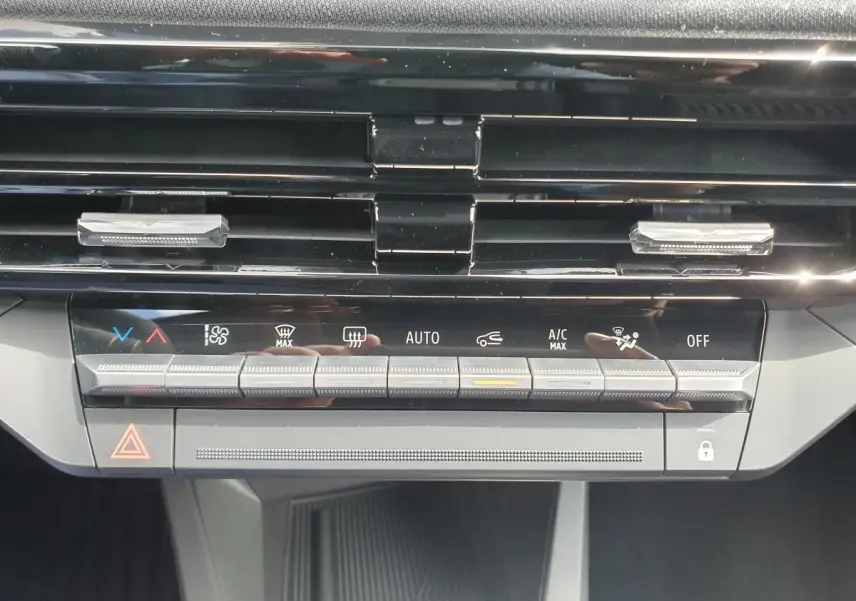 Gros plan sur la console centrale de la Renault Clio VI, montrant les commandes de climatisation et les aérateurs noirs.
