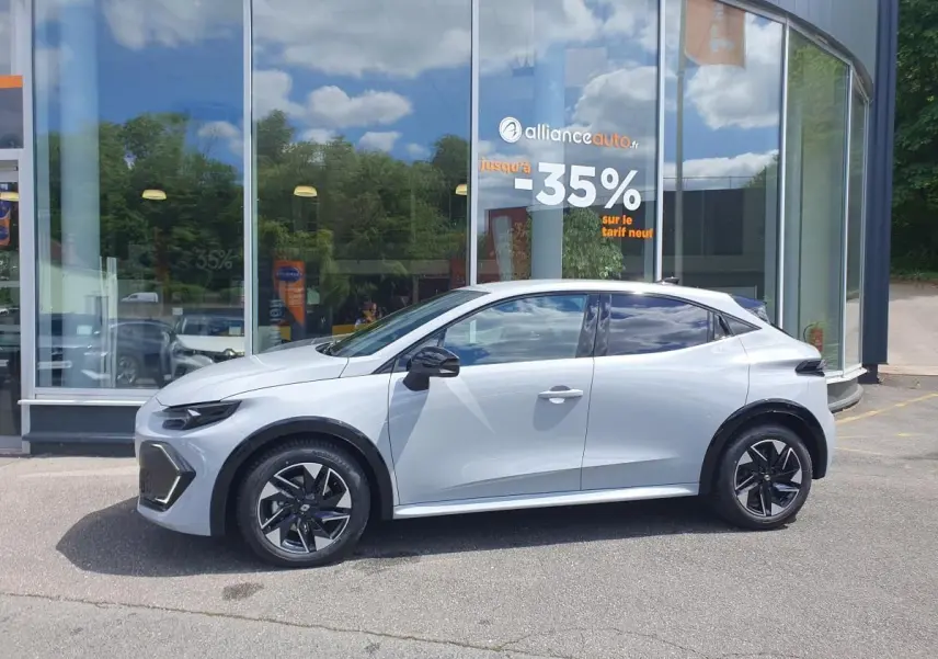 Profil droit de la Renault Clio VI gris Rafale, avec jantes alliage noir et vitres surteintées, devant une vitrine.