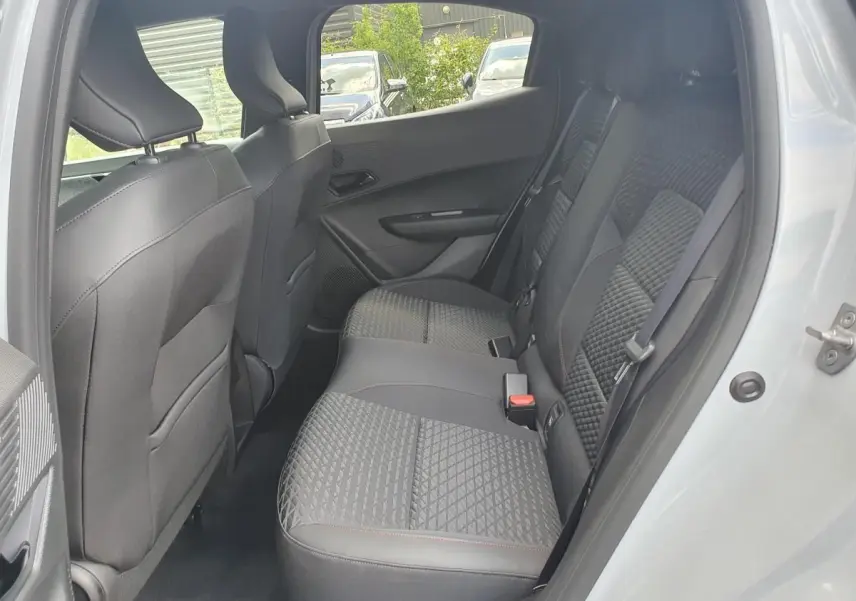 Vue intérieure arrière côté droit de la Renault Clio VI gris Rafale, montrant les sièges arrière en tissu et cuir avec surpiqûres rouges.
