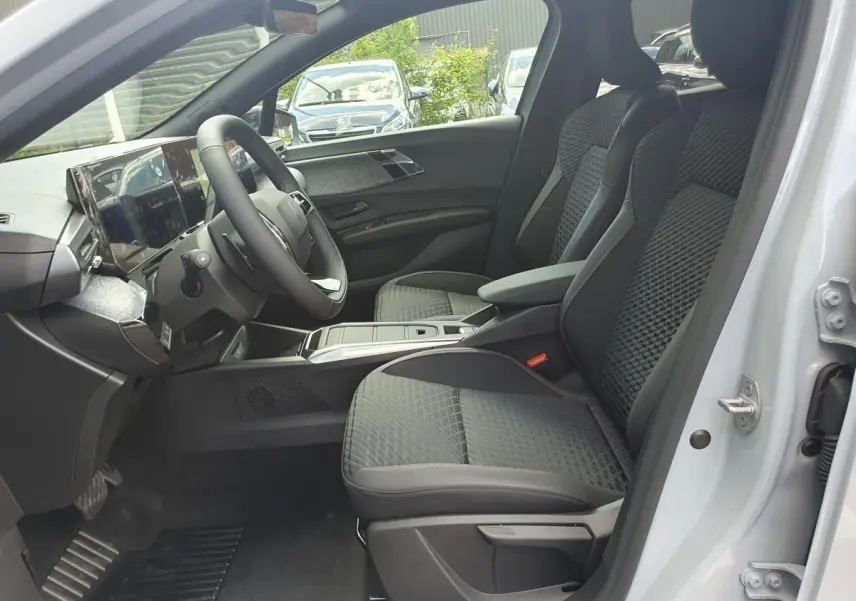 Vue intérieure côté conducteur de la Renault Clio VI avec sièges tissu noir et tableau de bord moderne.