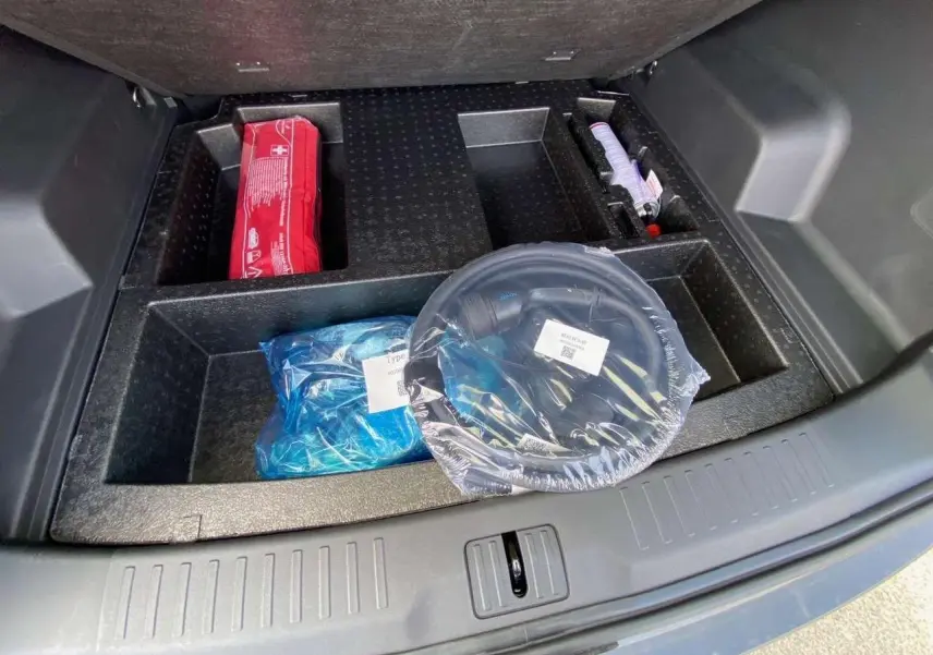 Coffre ouvert du JAECOO J7 1.5 PHEV Selective 2026, vue plongeante sur rangement avec accessoires emballés.