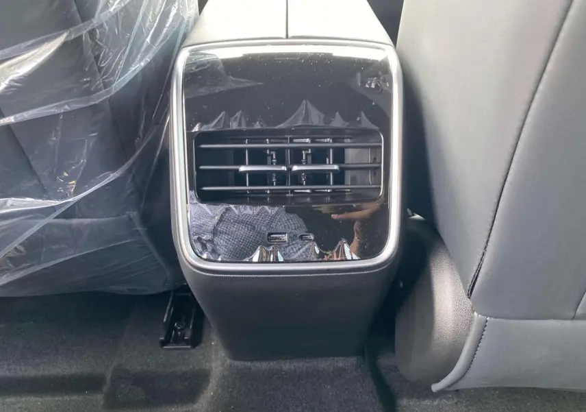 Vue rapprochée de la console arrière du JAECOO J7 1.5 PHEV en noir brillant avec prises USB visibles.