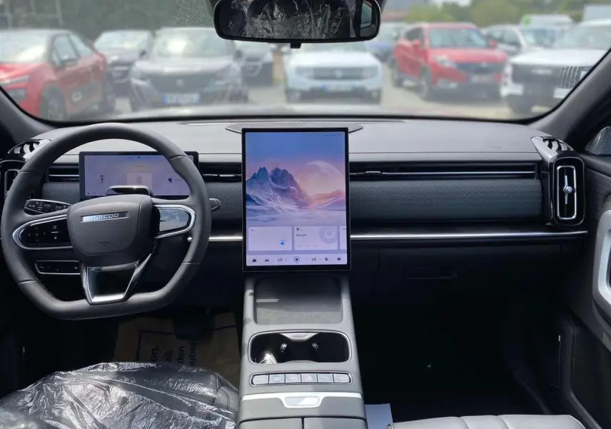 Vue intérieure avant du JAECOO J7 1.5 PHEV en noir, avec grand écran tactile vertical et volant multifonction.