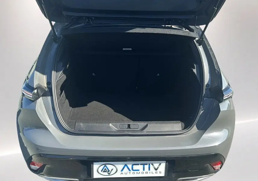 Vue arrière ouverte du coffre d'une Peugeot 308 gris selenium, mettant en valeur l'espace de chargement et les feux arrière LED.
