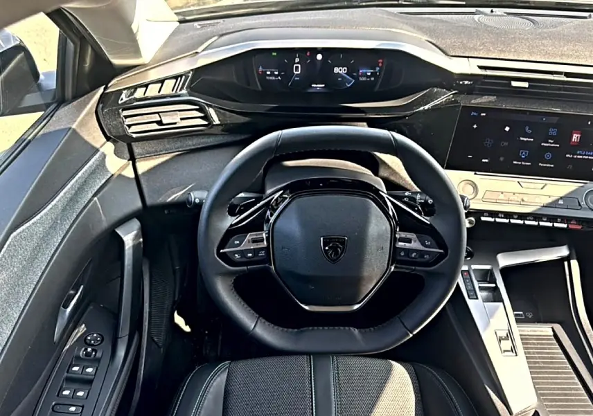 Vue intérieure centrée sur le volant multifonction noir et le tableau de bord digital du Peugeot 308 2025.