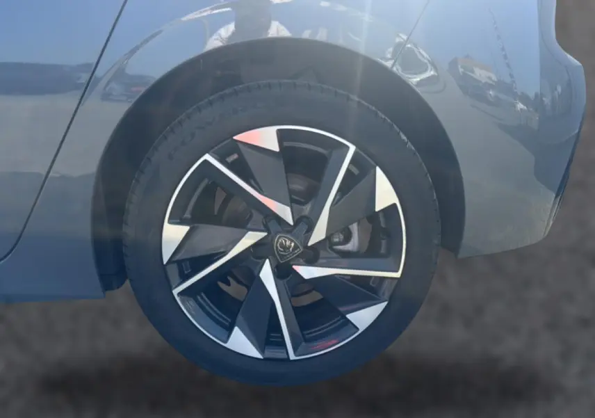 Gros plan sur la roue arrière droite d'une Peugeot 308 gris selenium avec jante alu au design moderne.