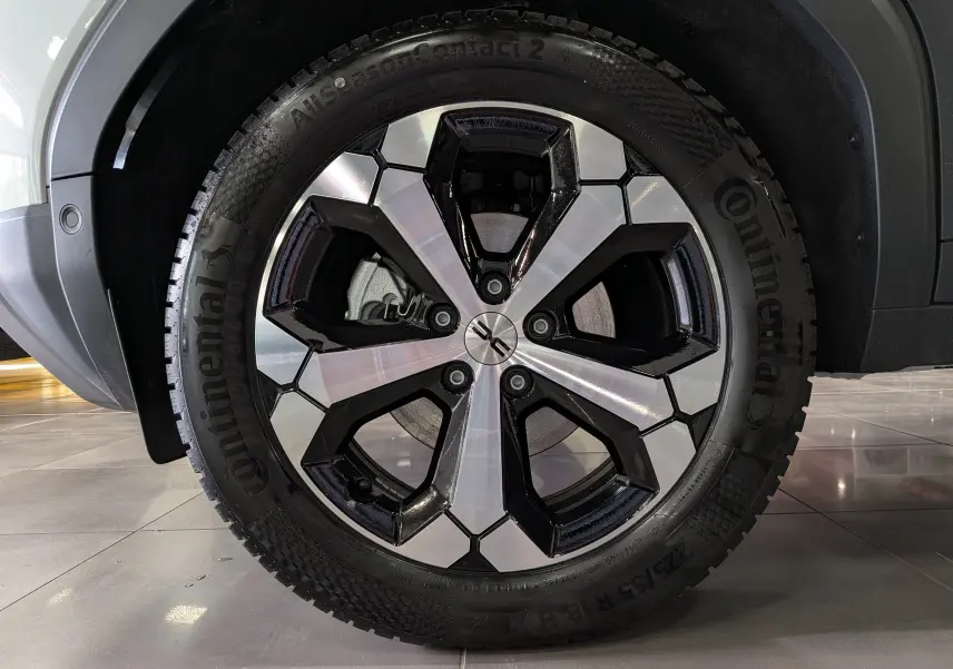 Gros plan sur la roue avant droite du Dacia Duster blanc Glacier, mettant en valeur la jante bi-ton noire et argentée.