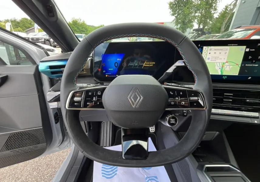 Vue intérieure centrée sur le volant cuir multifonctions de la Renault Clio 6 E-Tech 160 Esprit Alpine gris rafale, avec écran digital.