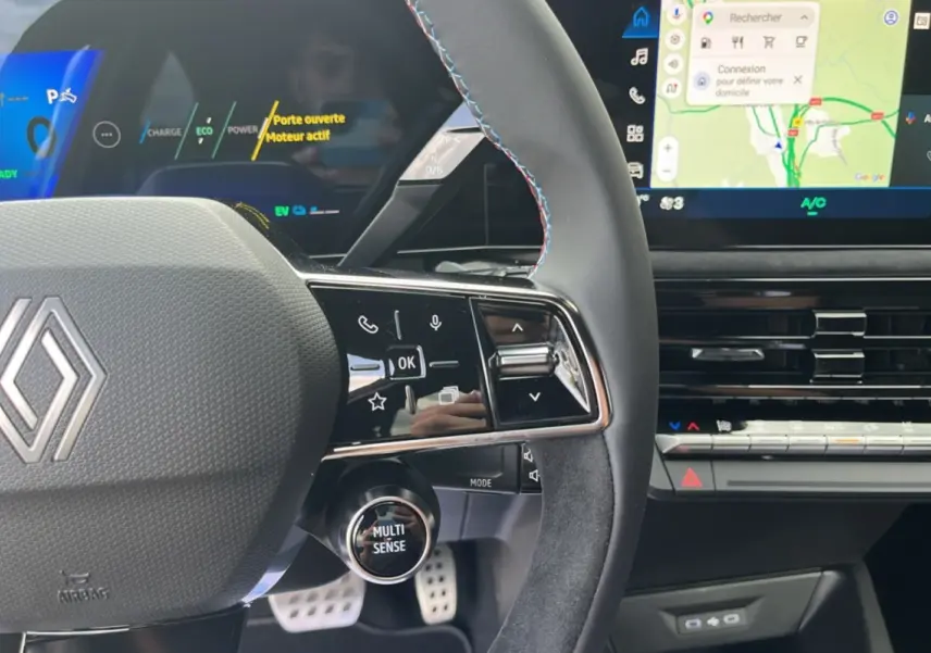 Gros plan sur le volant cuir multifonctions de la Renault Clio 6 E-Tech 160 Esprit Alpine avec tableau de bord numérique et écran tactile.